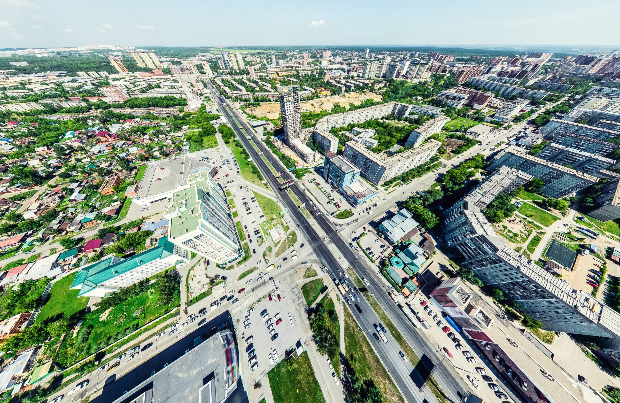 Aerial city view with crossroads and roads, houses, buildings, parks and parking lots. Sunny summer panoramic image